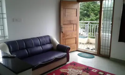 a living room with a couch and a door at Neo Nirmal Residency in Ooty