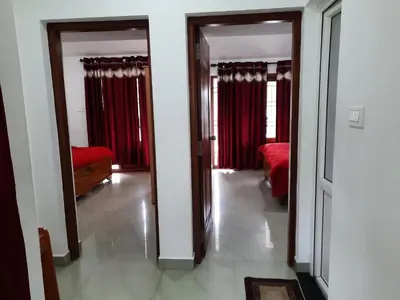 a living room with red curtains and a red couch at Neo Nirmal Residency in Ooty