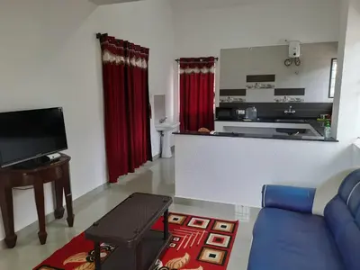 a living room with a blue couch and a kitchen at Neo Nirmal Residency in Ooty