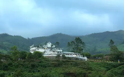 a white house on top of a hill at Elysium Garden in Munnar
