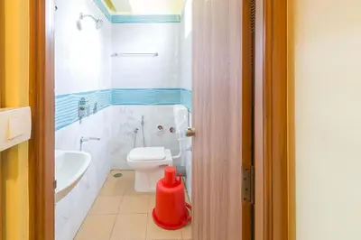 a bathroom with a white toilet and a sink at Sree Comforts in Kushālnagar