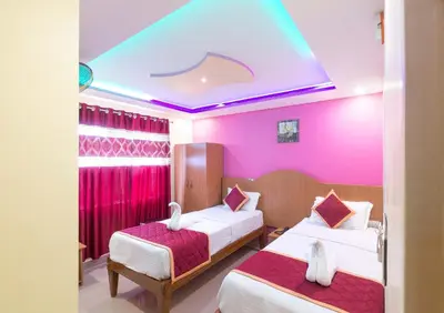 two beds in a room with pink walls at Sree Comforts in Kushālnagar