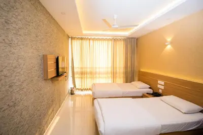 a hotel room with two beds and a window at Hotel Kapilavasthu in Palakkad
