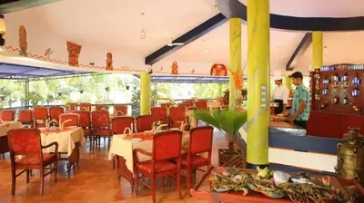 a restaurant with tables and chairs and people in the background at Kappad Beach Resort in Kappad