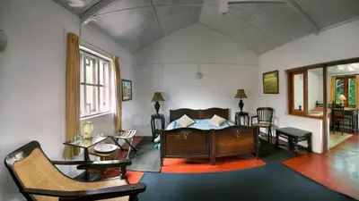a living room with a bed and a table and chairs at Neemrana's Wallwood Garden in Coonoor