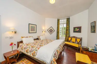 a bedroom with a bed and a table and a chair at Neemrana's Wallwood Garden in Coonoor