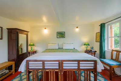 a bedroom with a large bed and two chairs at Neemrana's Wallwood Garden in Coonoor