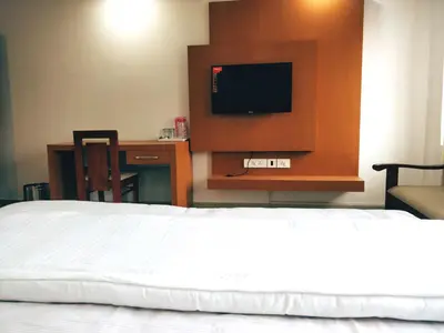 a hotel room with a bed and a flat screen tv at Prajapuri Hotel in Trichūr