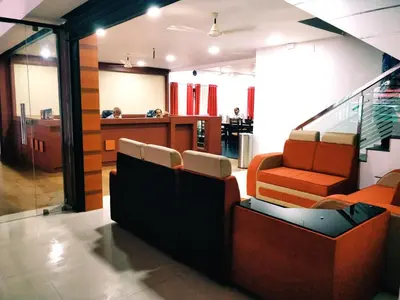 a lobby with orange chairs and a waiting room at Prajapuri Hotel in Trichūr