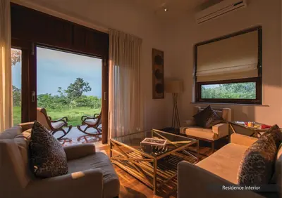 a living room with couches and a large glass door at The Serai Bandipur in Bandipūr