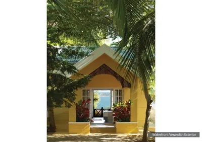 a yellow house with a palm tree in the foreground at The Serai Kabini in Begūr