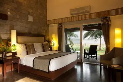 a bedroom with a large bed and a balcony at The Serai Kabini in Begūr