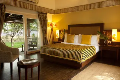 a bedroom with a king sized bed and a balcony at The Serai Kabini in Begūr