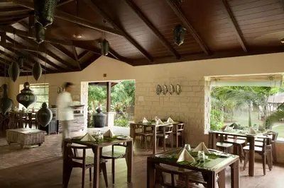 a restaurant with tables and chairs in a room at The Serai Kabini in Begūr