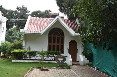 a small white house with a red roof at Poppys Vista Hotel in Thirumurugan Poondi