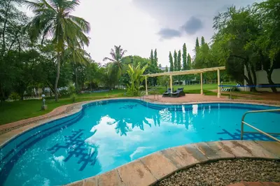 a large blue swimming pool with a gazebo at Poppys Vista Hotel in Thirumurugan Poondi