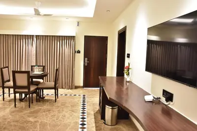 a hotel room with a dining table and a television at Poppys Vista Hotel in Thirumurugan Poondi