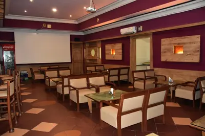 a room with tables and chairs and a projection screen at Poppys Vista Hotel in Thirumurugan Poondi