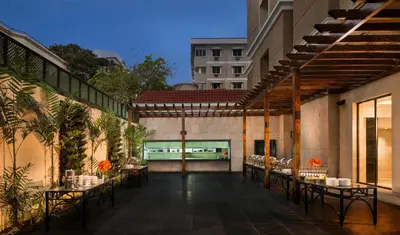 a patio with tables and chairs on a building at The Residency Towers Coimbatore in Coimbatore
