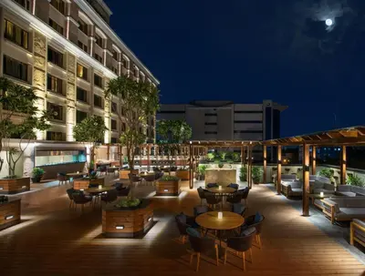 an outdoor patio with tables and chairs at night at The Residency Towers Coimbatore in Coimbatore