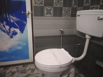a bathroom with a white toilet in a room at Landy Queen in Munnar