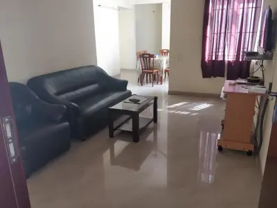 a living room with a black leather couch and a table at Tulip Suites in Coimbatore
