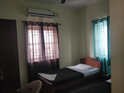 a small bedroom with a bed and two windows at Tulip Suites in Coimbatore
