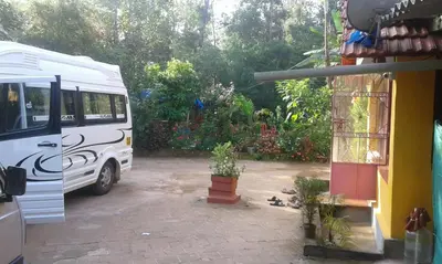 a white bus parked next to a house with plants at Dreams Home Estate Stay in Suntikoppa