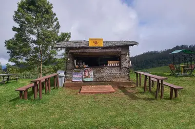 a small building with benches in a field at Accord Highland Hotel Ooty in Ooty