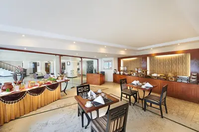 a restaurant with tables and chairs and a bar at Accord Highland Hotel Ooty in Ooty
