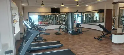 a gym with several treadmills and machines in a room at Accord Highland Hotel Ooty in Ooty