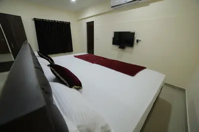 a bedroom with a white bed and a television at Shivalaya Residency in Trichūr