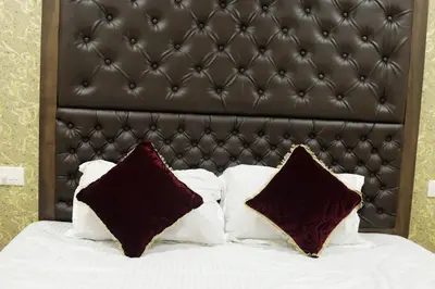 a bed with white pillows and a brown padded headboard at Shivalaya Residency in Trichūr