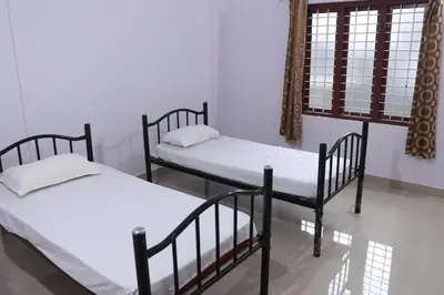 two twin beds in a room with a window at Anamala Serenity Homestay Kerala in Lakkidi