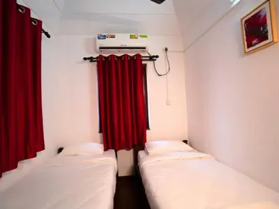 two beds in a room with red curtains at Anamala Serenity Homestay Kerala in Lakkidi