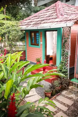 a small gingerbread house in a garden with plants at Anamala Serenity Homestay Kerala in Lakkidi