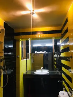 a yellow and black bathroom with a sink and a mirror at Mountain View cottage in Ooty