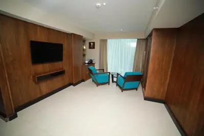 a hotel room with two chairs and a flat screen tv at YASH INTERNATIONAL in Kozhikode