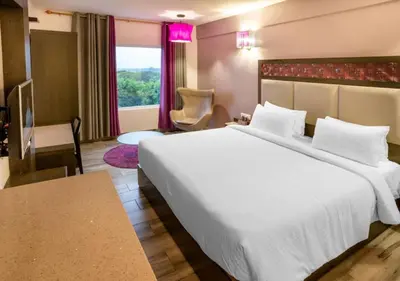 a hotel room with a large white bed and a window at Regency Palani by GRT Hotels in Palani