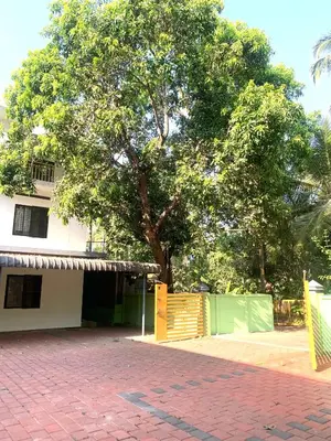 a tree in front of a building with a yellow gate at Airavatham Apartments in Guruvāyūr