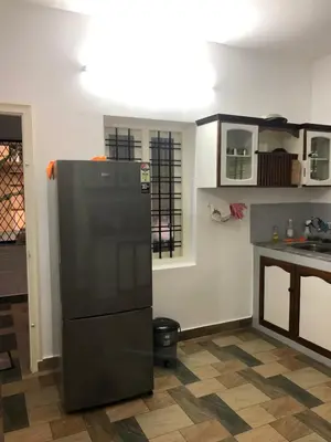 a kitchen with a black refrigerator in a room at Sannidhi Home stay in Guruvāyūr