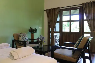 a room with two beds and a table and a window at Logan Camp Ooty in Coonoor
