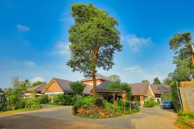 a house with a tree in the driveway at Morickap Resort in Vythiri