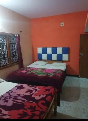a bedroom with two beds and an orange wall at Long Wood Hills Cottage in Ooty