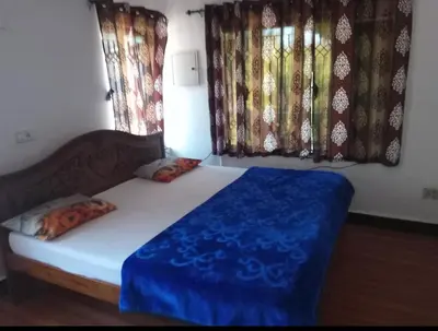 a bedroom with a bed with blue sheets and windows at Long Wood Hills Cottage in Ooty