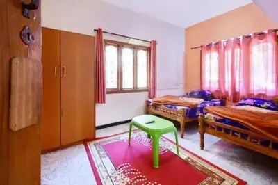 a room with two beds and a green stool in it at Long Wood Hills Cottage in Ooty