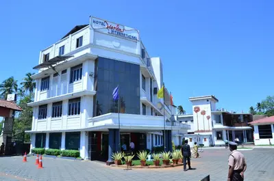 a large white building with a clock on it at Hotel Merlin International in Trichūr