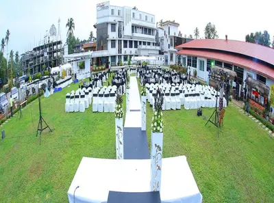 an outdoor event with white tables and chairs in a field at Hotel Merlin International in Trichūr