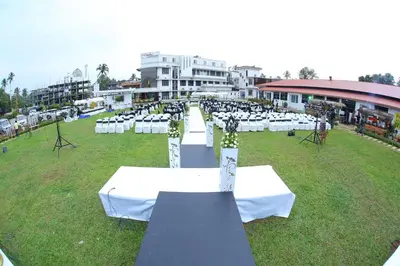 a group of tables with white cloths on a field at Hotel Merlin International in Trichūr
