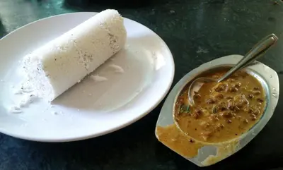 a piece of cake on a plate with a cup of soup at Hotel Villa Maryam in Kozhikode